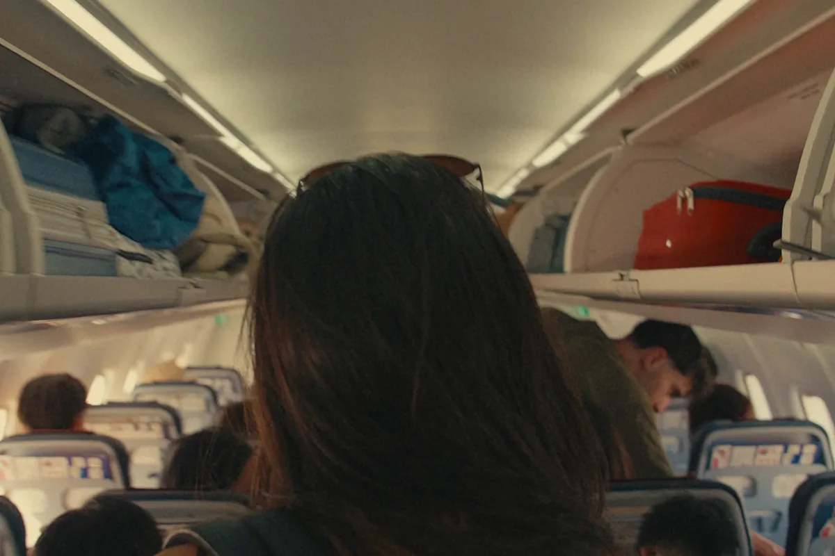 Lilian in the plane aisle, bag on her back